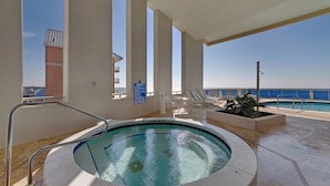 A hot tub with a view of the ocean, surrounded by lounge chairs and a pool. - Palazzo 1604 (Panama City Beach)