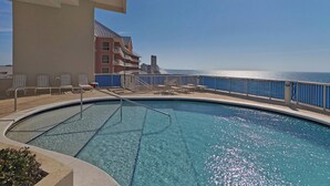 A pool area with a view of the ocean, lounge chairs, and a building with balconies. - Palazzo 1604 (Panama City Beach)