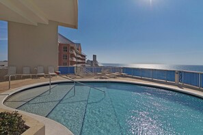 A pool area with a view of the ocean, lounge chairs, and a building with balconies. - Palazzo 1604 (Panama City Beach)