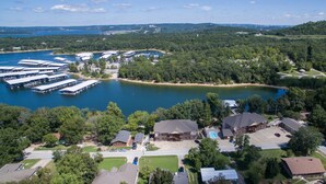 A lakeside property with multiple boat docks, a swimming pool, and a large building with a covered patio.