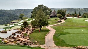 A golf course with a winding path, a pond, and a building with a chimney.