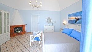 A bedroom with a bed, a dresser, a chair, a fireplace, and a painting on the wall. - Palazzo Rocco - Villa Red Moon in Love - 1 Room - 1 bath - 4 person - Sea 500 mt (Praiano)
