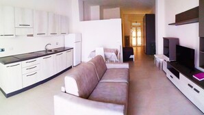 Un espacio moderno para vivir con kitchenette, un sofá, un televisor y una zona de comedor.
