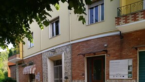 Un edificio con fachada de piedra, un acceso con baldosas y un cartel.