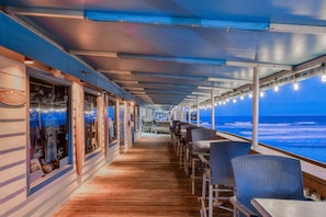 Ett däck på ett kryssningsfartyg med ett restaurangområde, bord och utsikt över havet.