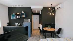 Un espacio habitable moderno y funcional con kitchenette, comedor y cama.