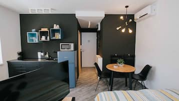Um espaço de estar moderno e compacto, com cozinha compacta, área de refeições e cama.