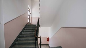 Una escalera con barandilla, un extintor en la pared y un interruptor de luz.