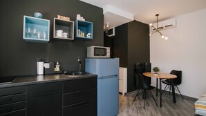 Una cocina compacta con un refrigerador azul, un microondas y un pequeño comedor con una mesa y sillas.