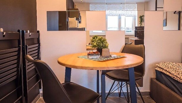 Un comedor moderno con una mesa redonda, sillas negras y una lámpara colgante.