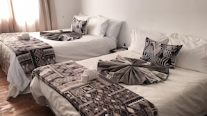 Una habitación de hotel con dos camas, cada una con mantas y almohadas estampadas.