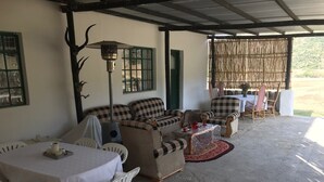 Un espacio de descanso al aire libre techado, con mesa, sillas y un sofá.