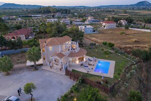 Ein großes Haus mit Swimmingpool, umgeben von einem eingezäunten Garten und Blick auf die Landschaft.