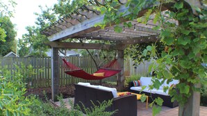 A covered outdoor seating area with wicker furniture and a hammock.