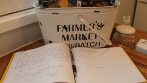 A bucket labeled "Farmer's Market" filled with books and a notebook with handwritten notes.