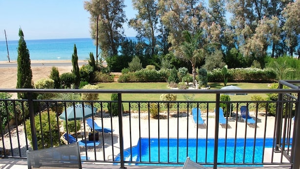 Ein Poolbereich mit Liegestühlen und Blick auf Strand und Meer.
