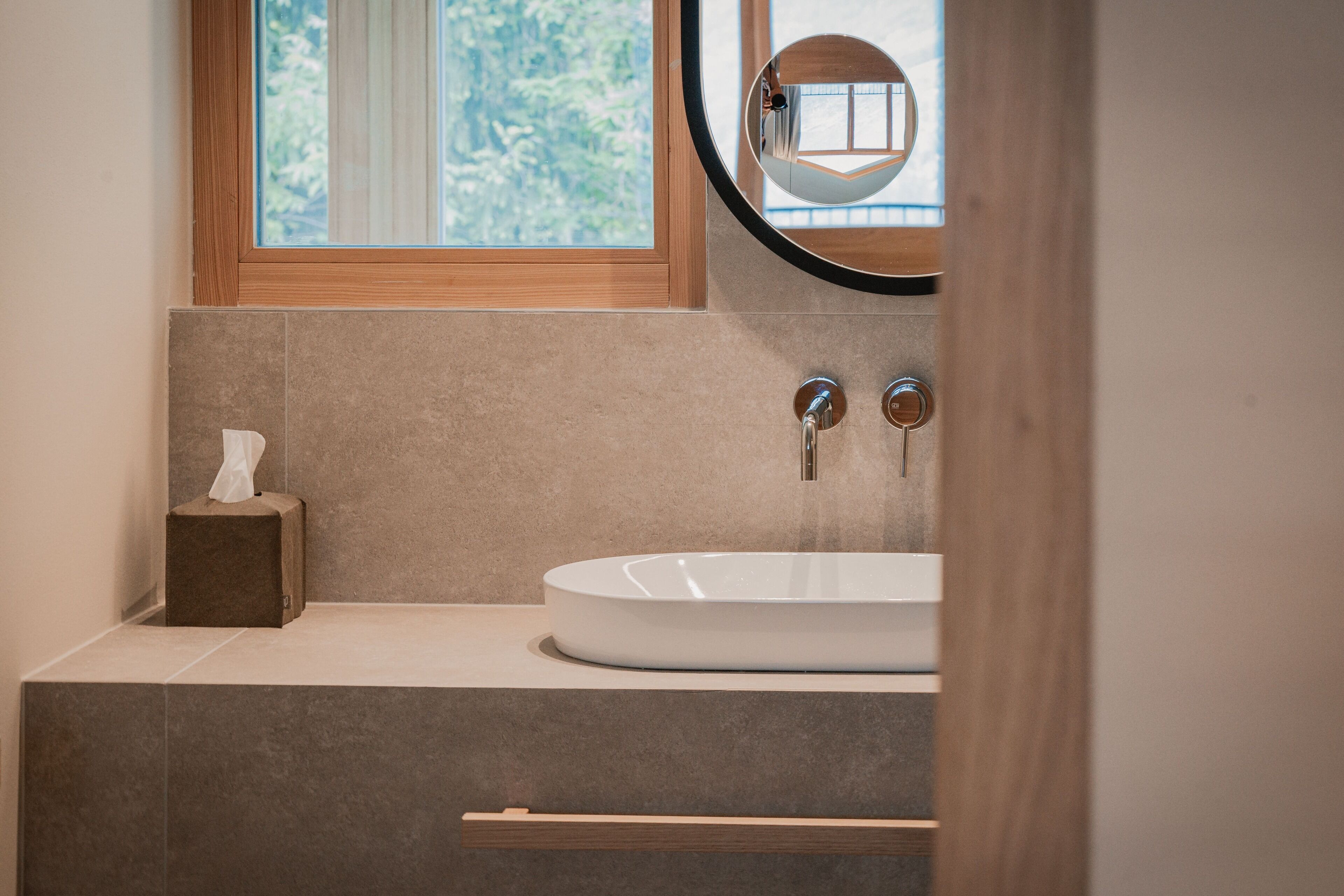 Ein Badezimmer mit Waschbecken, Holzfensterrahmen und Spiegel.