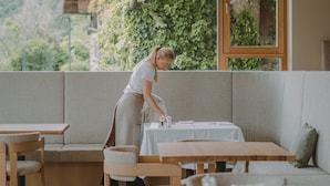 A modern dining area with wooden tables and benches, large windows with a view of greenery and a building. - Niedermair Nature Retreat (Parcines)