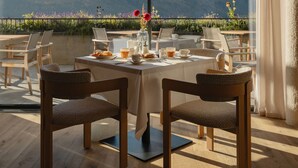 A dining area with a table set for two, overlooking a mountainous landscape. - Niedermair Nature Retreat (Parcines)