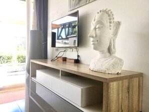 A modern living room with a wooden console table, a mounted flat-screen TV, and a white bust sculpture.