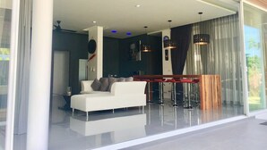 Ein modernes Wohnzimmer mit einem weißen Sofa, einem Holzesstisch und einer Glastrennwand.