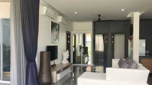 Ein modernes Wohnzimmer mit einem weißen Sofa, einer großen Vase und einem Flachbildfernseher.