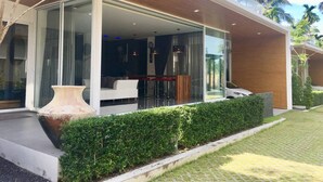 Ein modernes Haus mit Glasfassade, Außenbereich mit Sitzgelegenheiten und einer großen Vase.