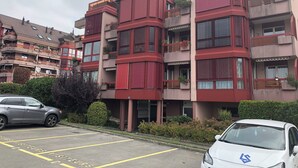A multi-story residential building with balconies, a parking lot, and a hedge. - Large Studio Near Epfl And Lausanne City Center (Ecublens)
