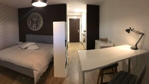 A bedroom with a bed, a nightstand, a wall clock, and a desk with a chair. - Large Studio Near Epfl And Lausanne City Center (Ecublens)