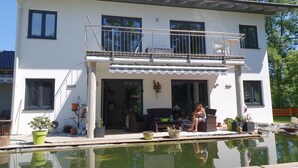 Una casa a due piani con un balcone, una piscina e mobili da giardino.