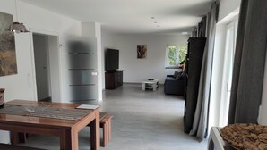 Un soggiorno moderno con un tavolo da pranzo in legno, un divano e una televisione.