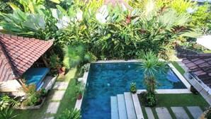 A rectangular swimming pool surrounded by lush greenery and a tiled roof structure. - Villa Semua Suka in the Ricefields of Penestanan (Ubud)
