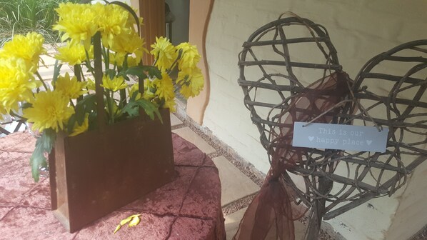 A potted yellow flower arrangement and a heart-shaped wooden structure with a sign stating "This is our happy place".