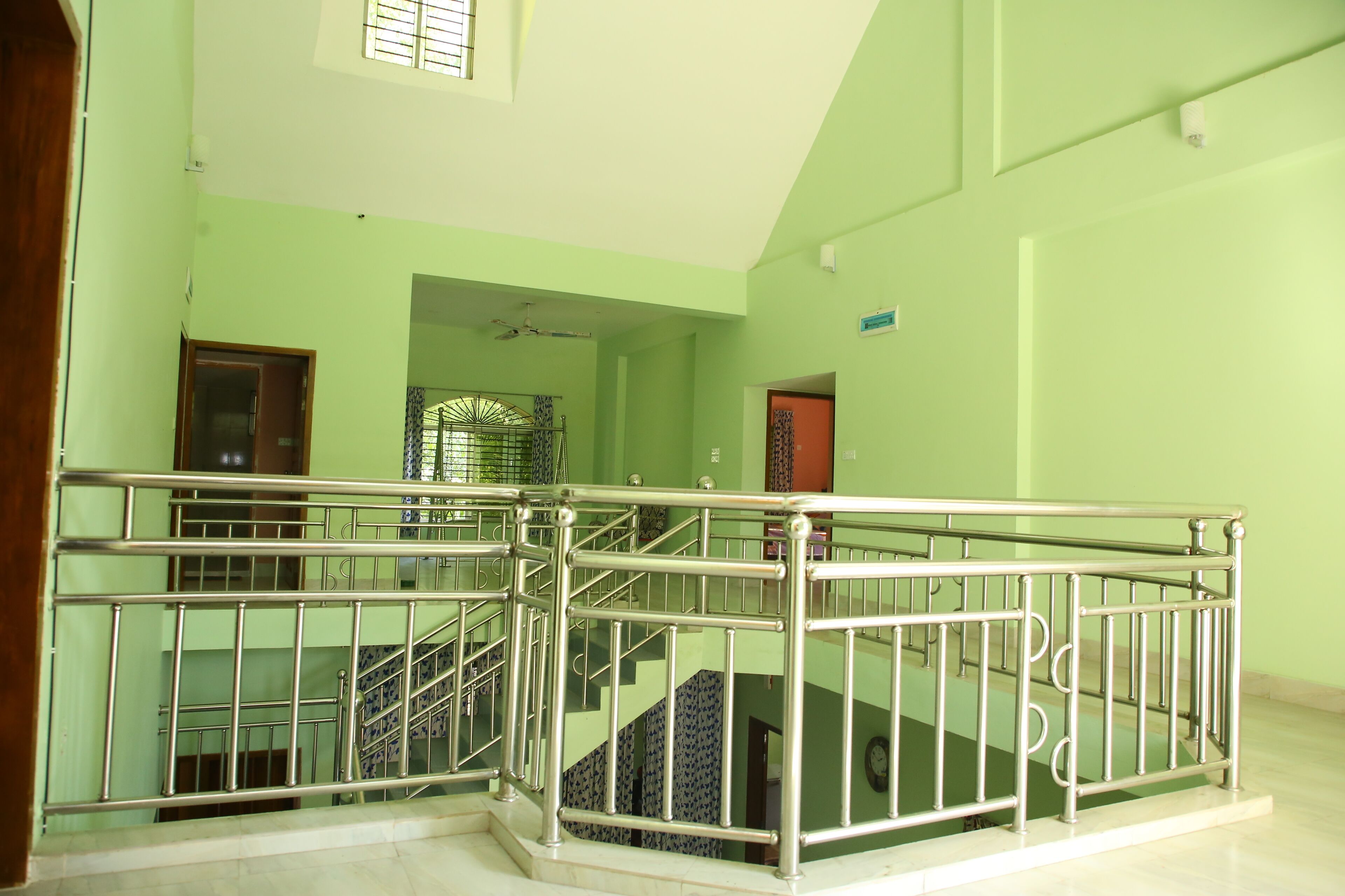 Ein mehrgeschossiges Interieur mit Metallgeländer, einer Treppe und einer grünen Wand.