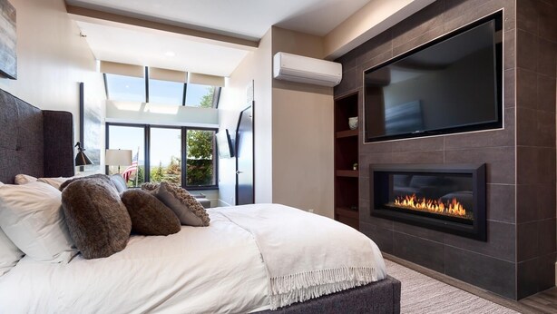 A modern bedroom with a large bed, a fireplace, a TV mounted on the wall, and a view of the outdoors. - Modern Magic At Park City Base Studio Bedroom Condo by RedAwning (Park City)