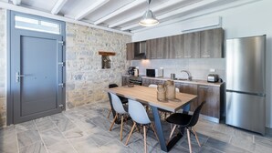 Una cocina moderna con paredes de piedra, armarios de madera, un refrigerador de acero inoxidable y una zona de comedor con mesa y sillas de madera.