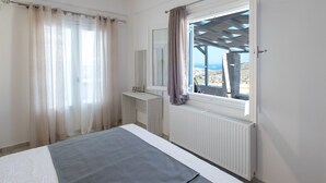 Un dormitorio con cama, ventana con cortinas, radiador y vistas al paisaje.