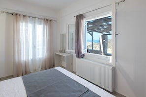 Un dormitorio con cama, ventana con cortinas, radiador y vistas al paisaje.
