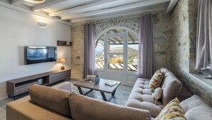 Una sala de estar con televisor, sofá, mesa de centro y paredes de piedra.