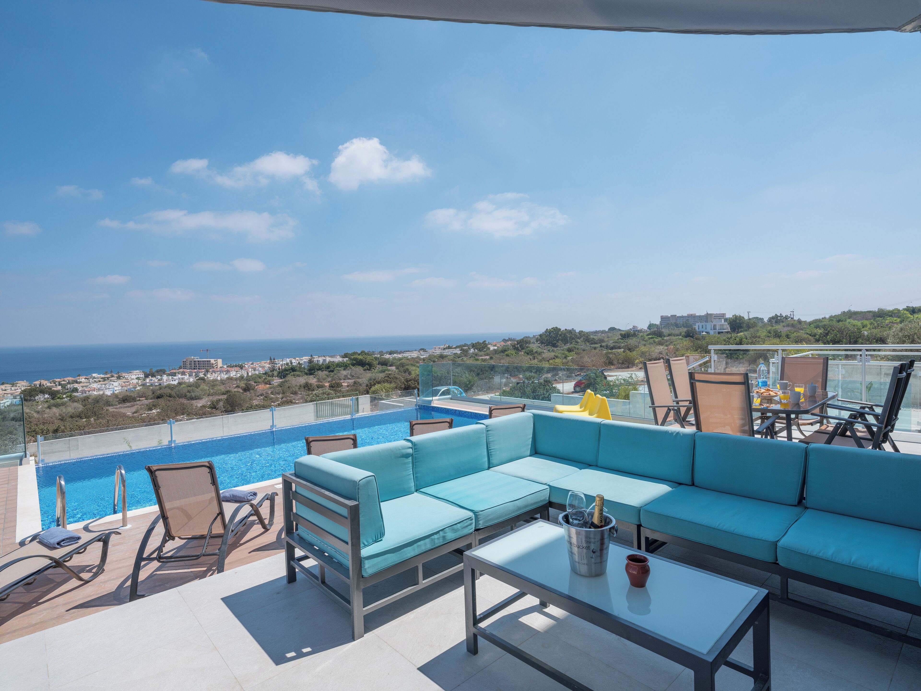 Eine Dachterrasse mit Pool, Sitzgelegenheit und freiem Blick auf Stadt und Meer.