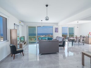 Relax in this stylish living area with a sofa, dining table, and TV, leading to a balcony with a sea view.