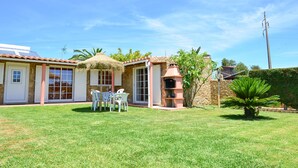 Ein Haus mit Terrasse, Grillplatz und kleinem Garten.