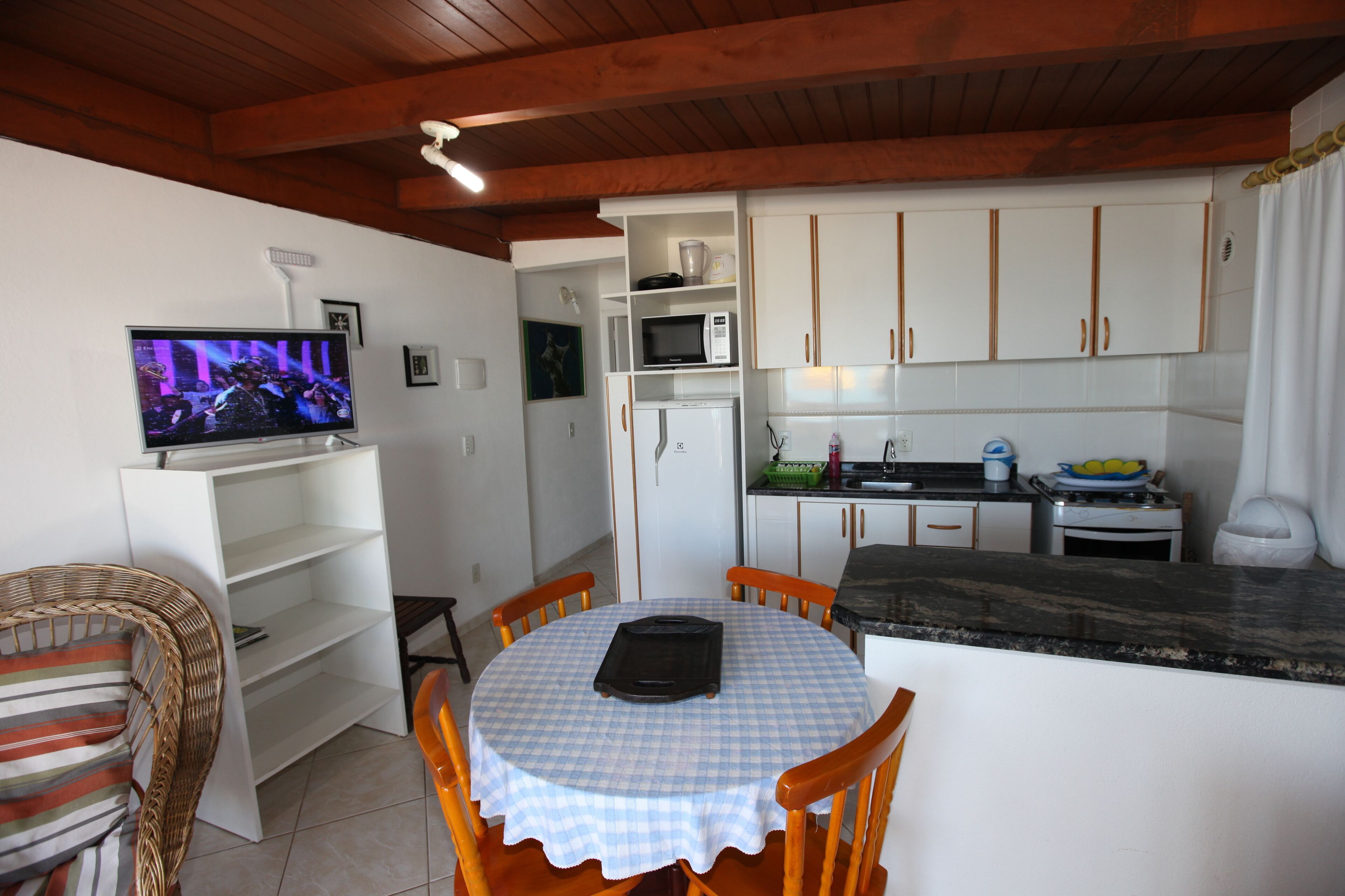 A compact kitchen with white cabinets, a microwave, and a small dining area with a checkered tablecloth.