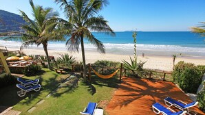Un patio frente a la playa con sillones de descanso, una hamaca y vista al océano.