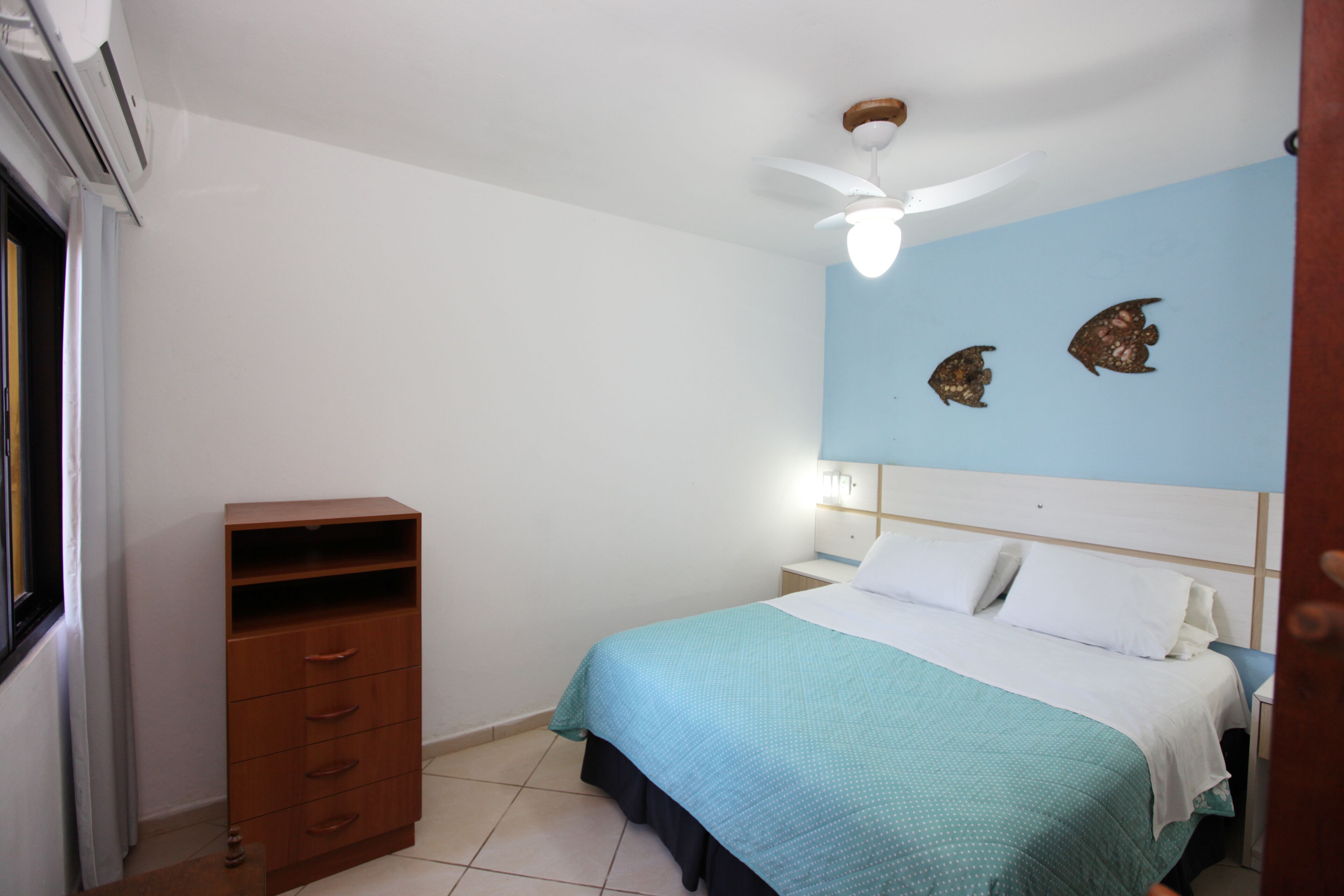 A bedroom with a bed, a nightstand, a dresser, and a ceiling fan.
