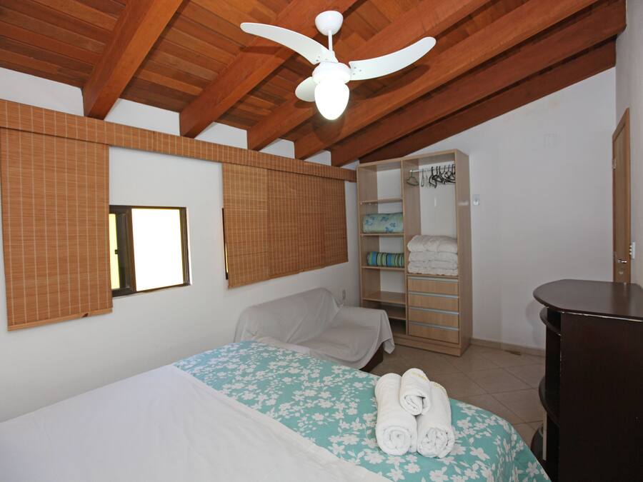 Un dormitorio con cama, ventilador de techo, armario y ventana.