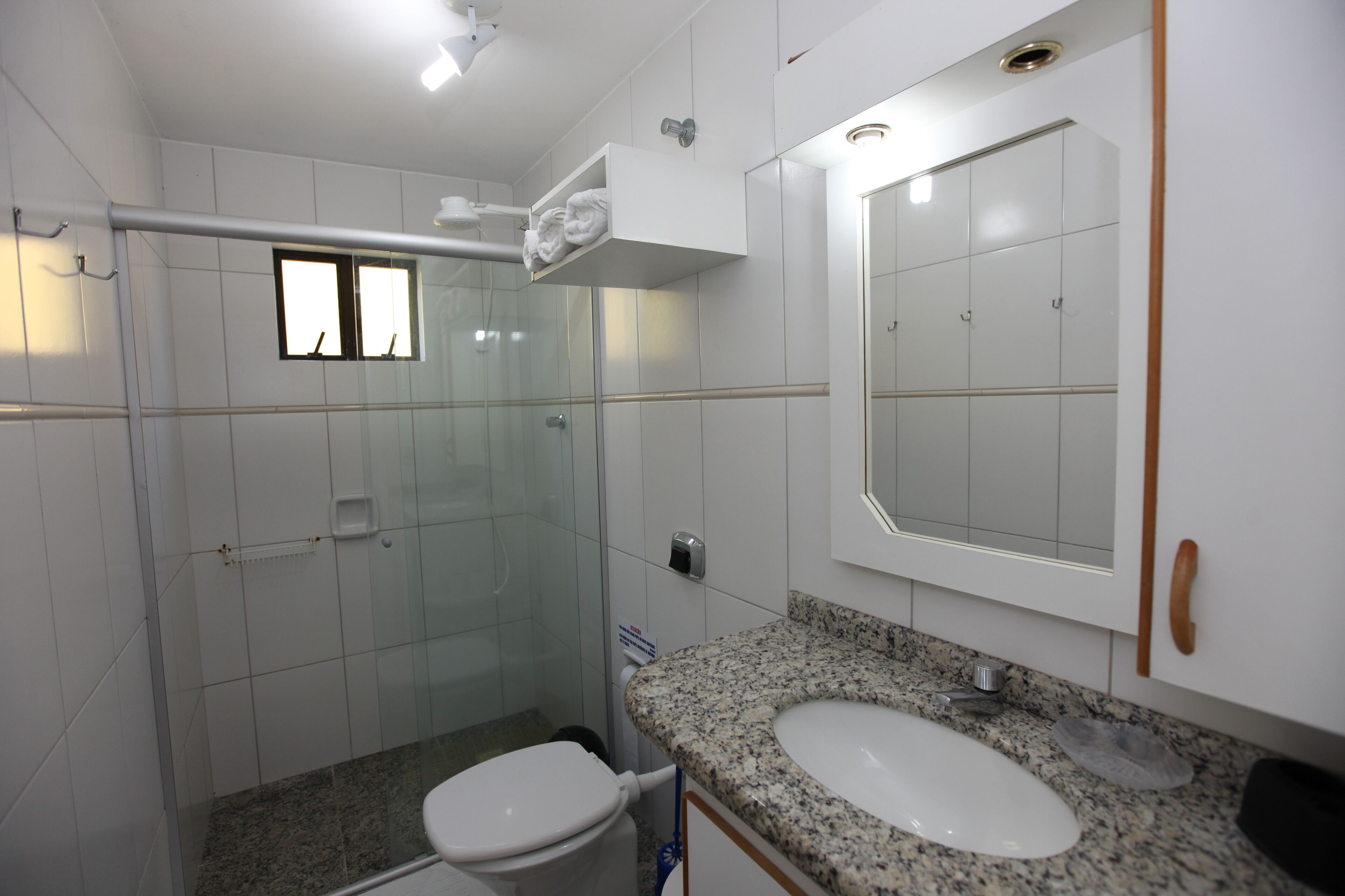 Une salle de bain moderne dotée d’une douche à parois de verre, d’un comptoir en granit et d’un grand miroir.