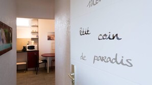 A hallway with a kitchen area, a dining table, and a door with partially visible text.