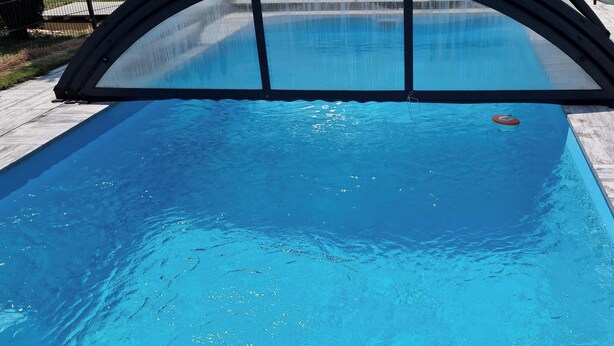 A swimming pool with a safety cover, surrounded by a tiled deck.