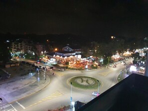 Vista nocturna de una glorieta con una plaza central, rodeada de edificios y farolas.